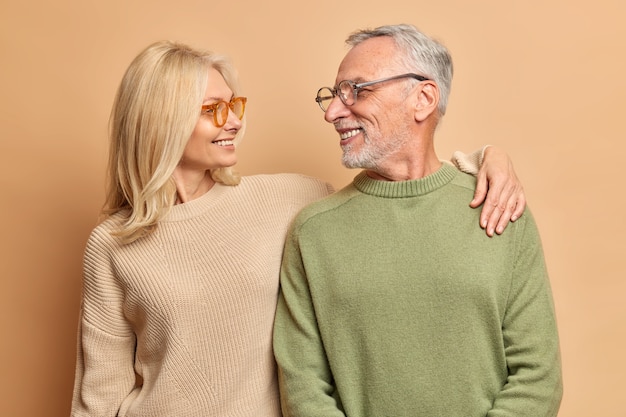 La mujer de mediana edad que se preocupa abraza a su marido se ve con amor y una amplia sonrisa