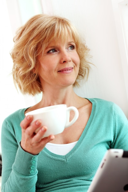 Mujer de mediana edad relajante con tableta comper