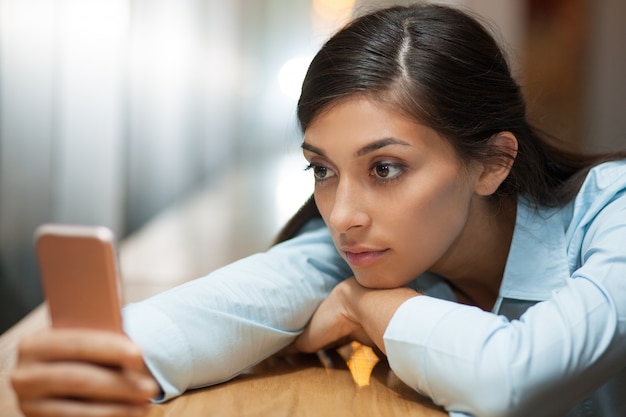 La mujer de mediana edad tumbado en la mesa con Smartphone