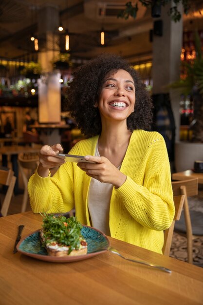 Mujer mediana tomando fotos de comida