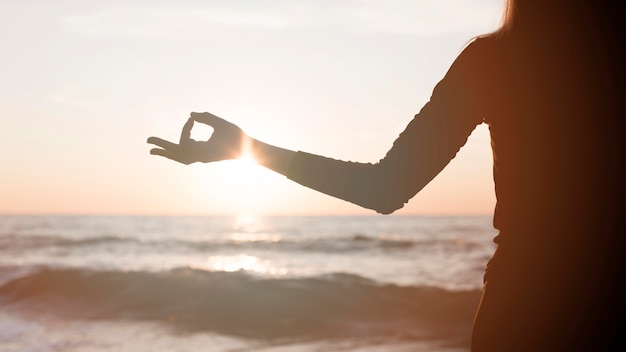 Foto gratuita mujer meditando al atardecer en la playa