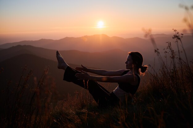 Mujer meditando está sentada sobre la hierba en las montañas