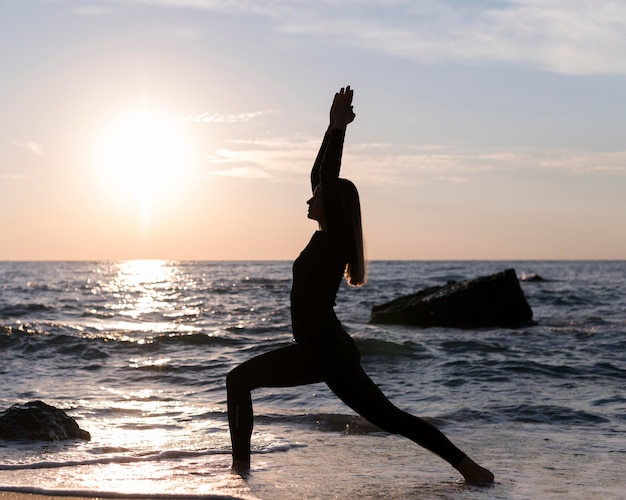 Mujer meditando en la playa al atardecer