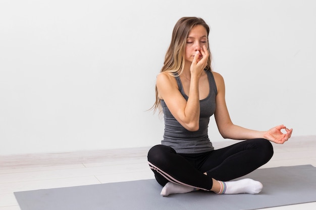 Mujer meditando sobre una estera de fitness con espacio de copia