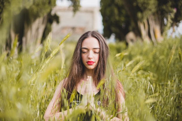 Mujer, meditar, alto, pasto o césped