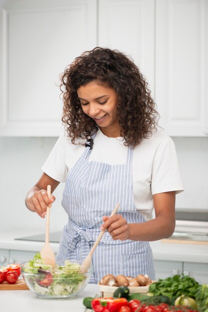 Mujer mezclando una ensalada con cuchara de madera