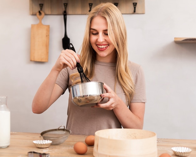 Foto gratuita mujer mezclando los huevos en un recipiente metálico