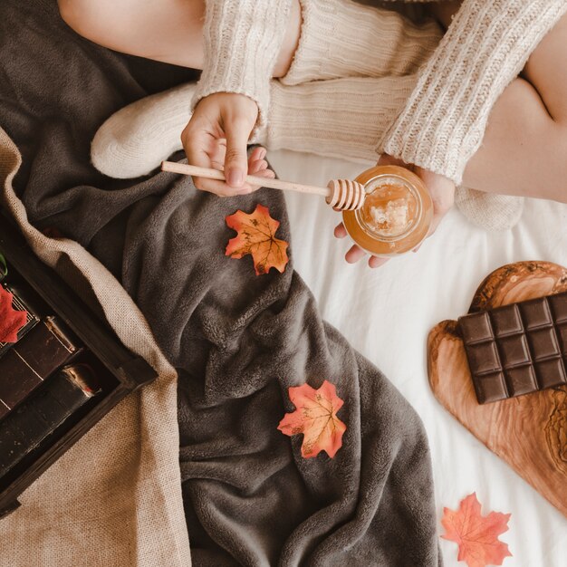 Mujer con miel cerca de libros y chocolate