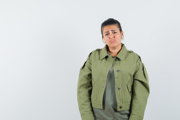 Mujer mirando al frente con chaqueta, camiseta y aspecto humilde.