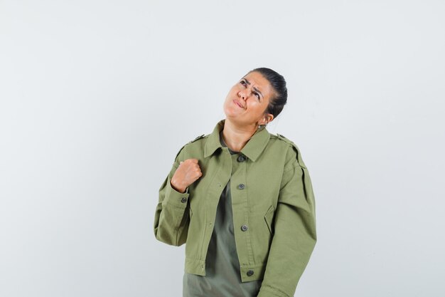 mujer mirando hacia arriba en chaqueta, camiseta y mirando pensativo