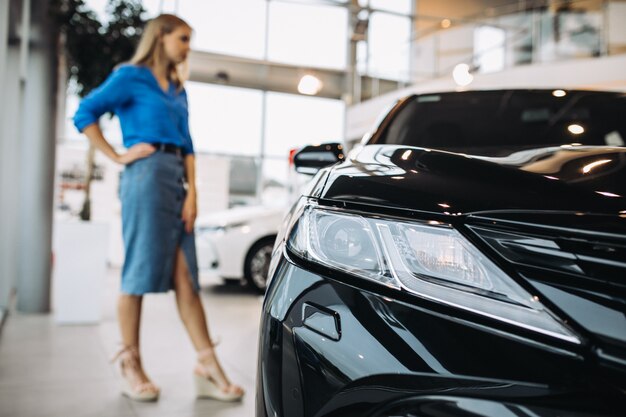 Mujer mirando un automóvil en una sala de exposición de automóviles