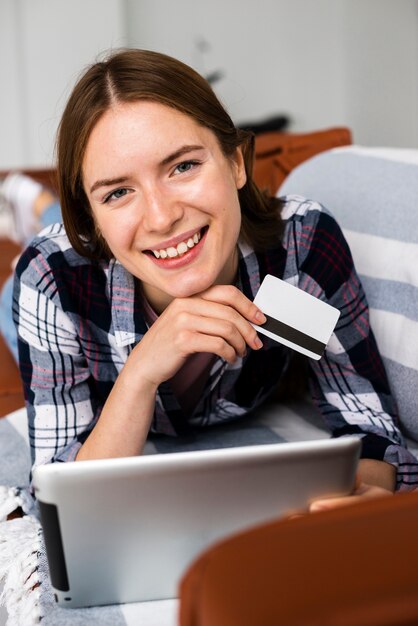 Mujer mirando a la cámara y sosteniendo una tarjeta de crédito