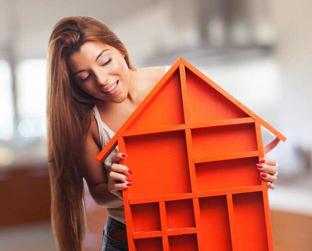 Mujer mirando una casa de juguete naranja