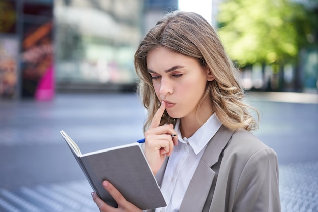 Mujer mirando concentrada mientras lee sus notas preparándose para entrevistar a una mujer de negocios en traje wri