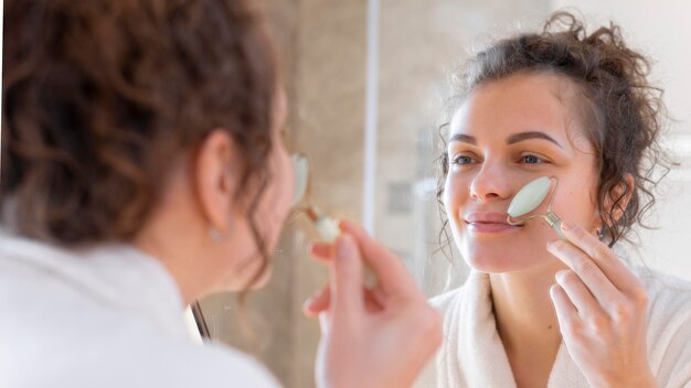 Mujer mirando en el espejo y haciendo masaje facial