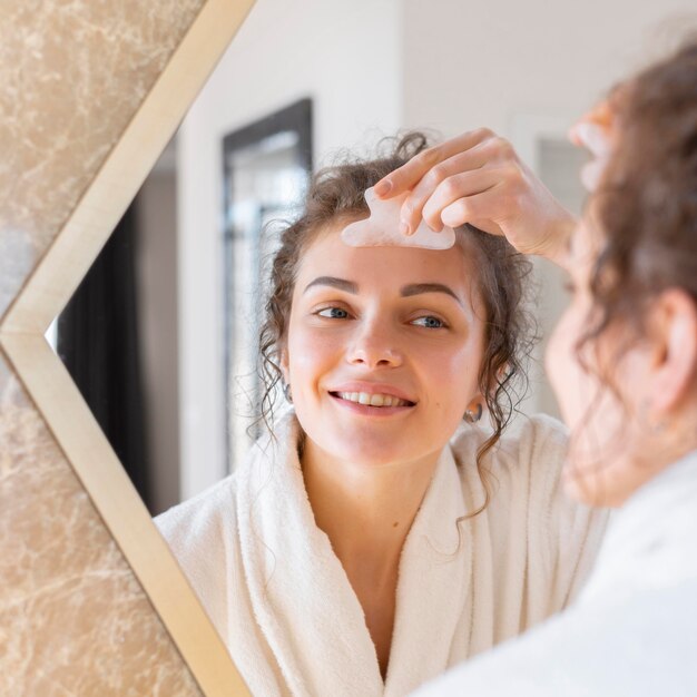 Mujer mirando en el espejo y haciendo masaje facial