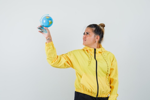 Mujer mirando el globo de la escuela en traje deportivo y mirando esperanzado, vista frontal.