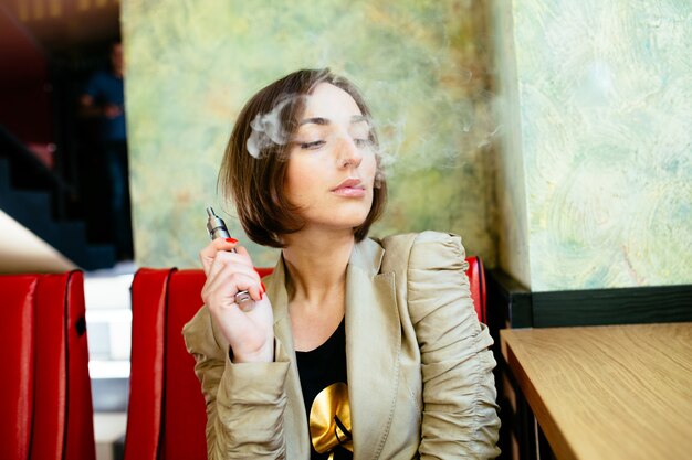 Mujer mirando el humo de su cigarro electrónico