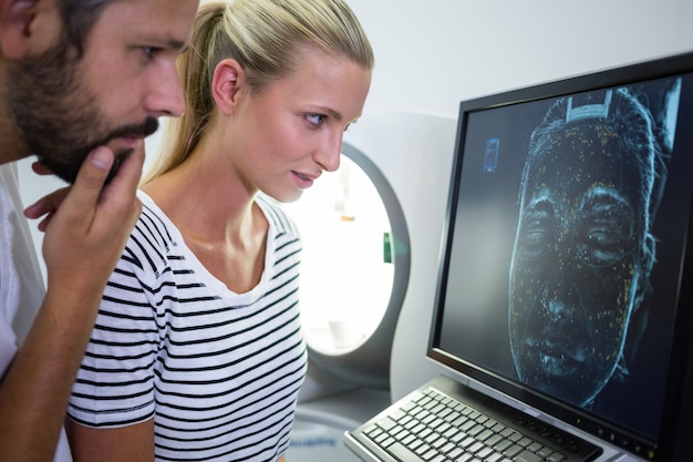 Mujer mirando el informe de exploración de resonancia magnética en la pantalla de la computadora