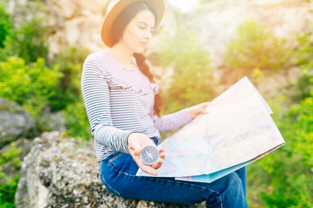 Mujer mirando a mapa sentada en una roca