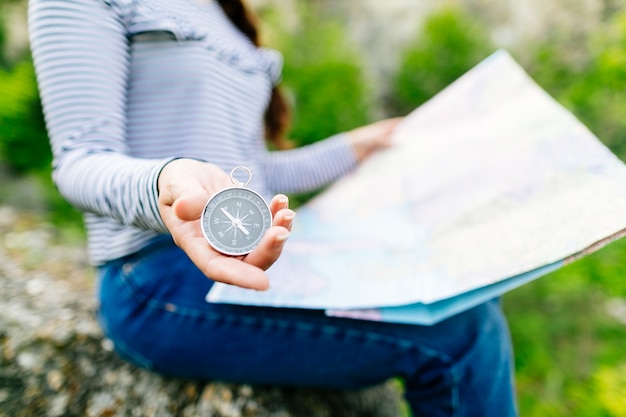 Mujer mirando a mapa sentada en una roca