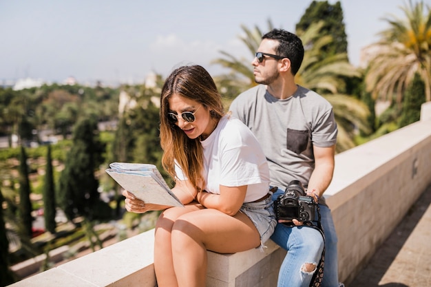 Mujer mirando en el mapa sentado con su novio en el parque