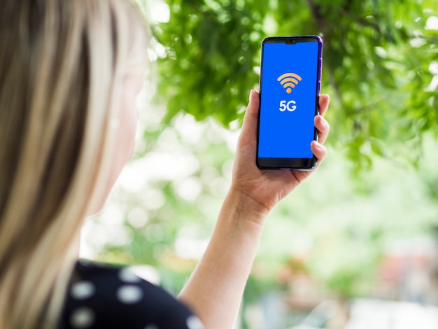 Mujer mirando la pantalla del teléfono con 5g en pantalla