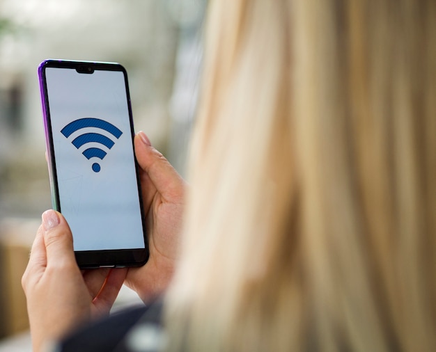 Mujer mirando la pantalla del teléfono con logo wifi