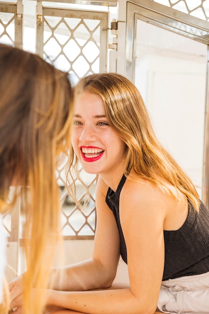 Mujer mirando a su amiga sonriente sentada en la cabina de la noria