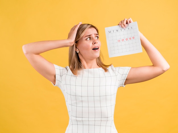 Foto gratuita mujer mirando su calendario de menstruación con miedo