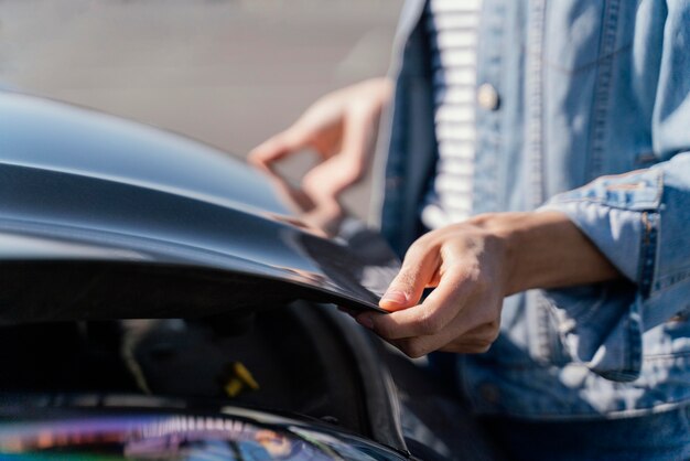 Mujer mirando su coche para resolver un problema