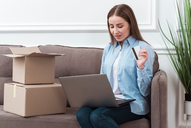 Mujer mirando su portátil y con tarjeta de crédito