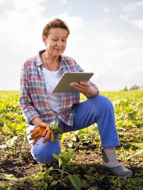 Mujer mirando su tableta mientras sostiene algunas zanahorias