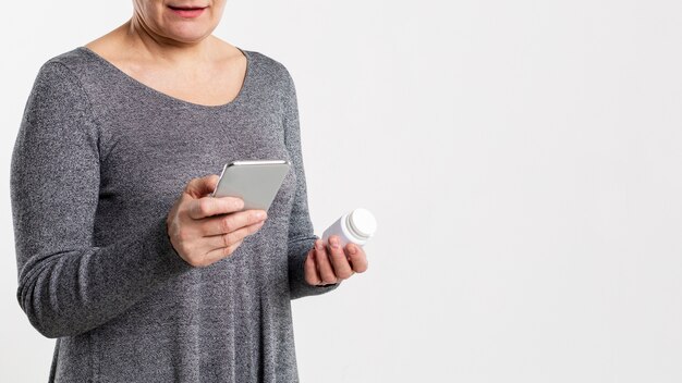Mujer mirando sus píldoras en internet usando un teléfono inteligente