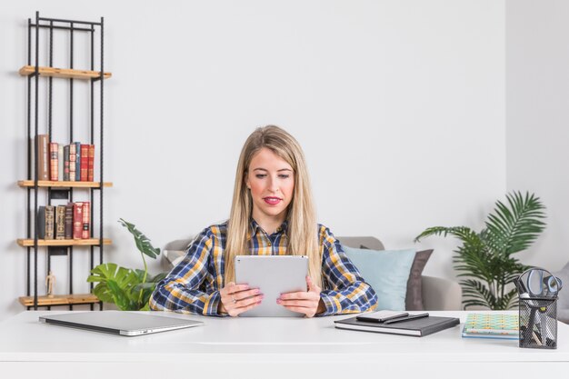 Mujer mirando tableta digital en lugar de trabajo en casa