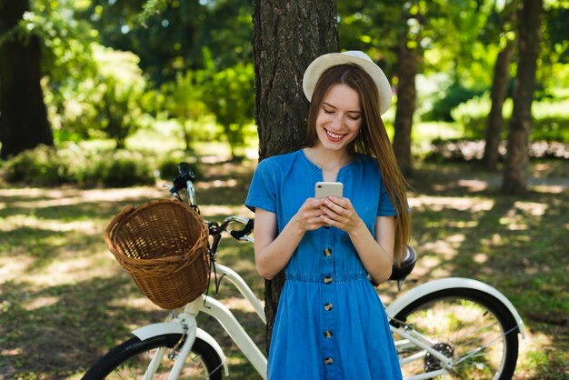 Mujer mirando el teléfono junto a la bicicleta