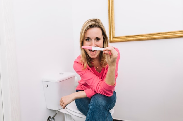 Mujer mirando a test de embarazo en baño