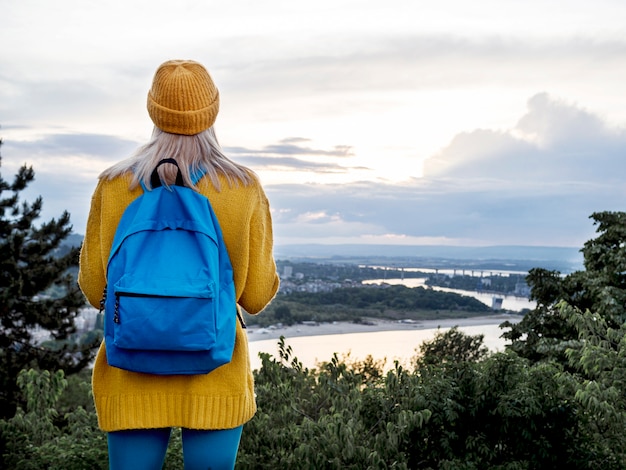 Foto gratuita mujer con mochila admirando la vista a la montaña