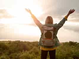 Foto gratuita mujer con mochila al atardecer en la naturaleza