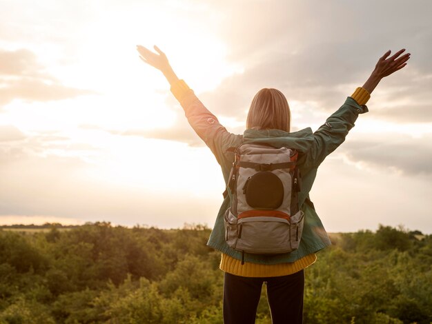 Mujer con mochila al atardecer en la naturaleza