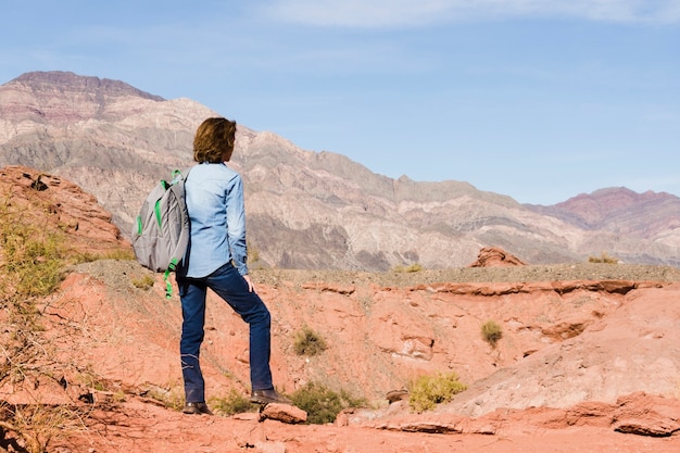 mujer con mochila disfrutando de paisaje de montaña