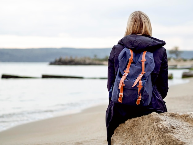 Foto gratuita mujer con mochila en la orilla del mar