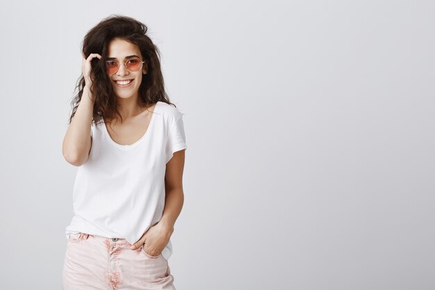 Mujer de moda atractiva en gafas de sol sonriendo despreocupada