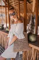 Foto gratuita mujer de moda en blanco detrás de un café de madera