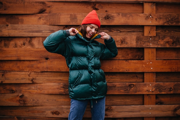 Mujer de moda de buen humor posando en la pared de madera