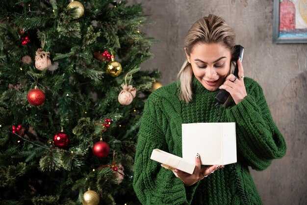 Mujer de moda elegante en suéter verde hablando por teléfono