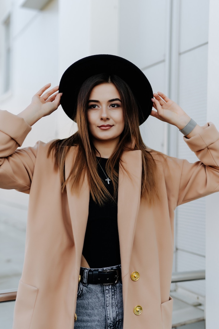 Foto gratuito mujer de moda con estilo en sombrero negro de pie y posando al aire libre.