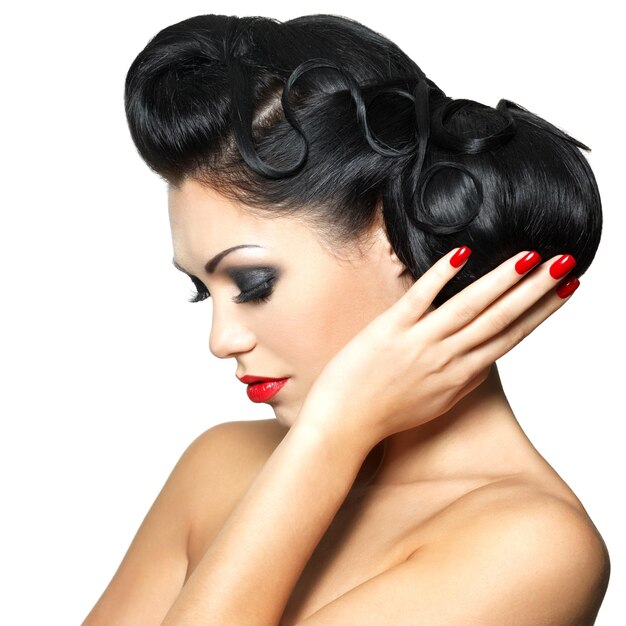 Mujer de moda hermosa con labios rojos, uñas y peinado creativo - aislado en la pared blanca