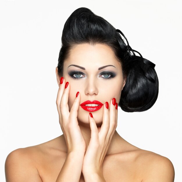 Mujer de moda hermosa con labios rojos, uñas y peinado creativo