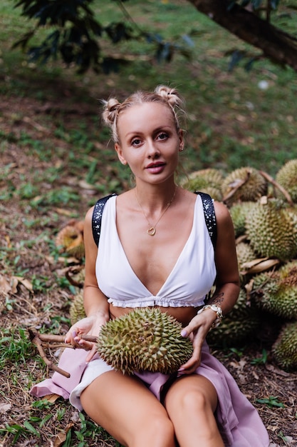 Mujer de moda joven en un campo tropical con frutos de durian